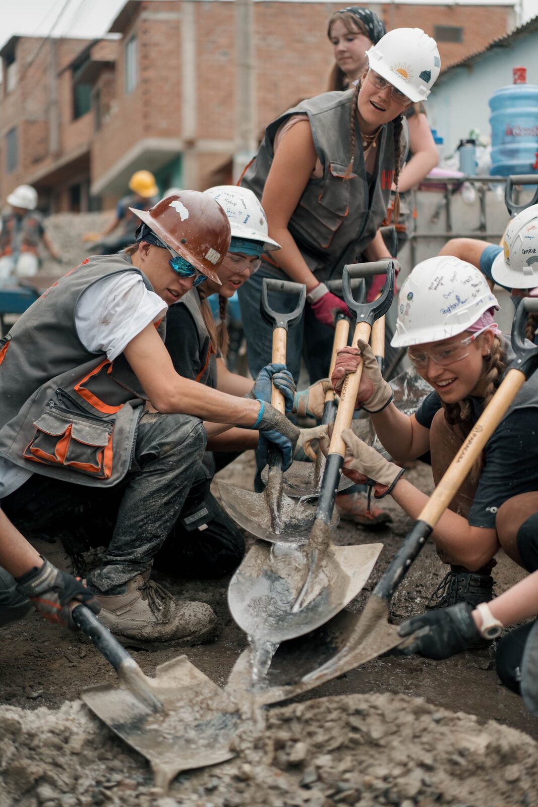 HXP Builders shoveling concrete together on a worksite